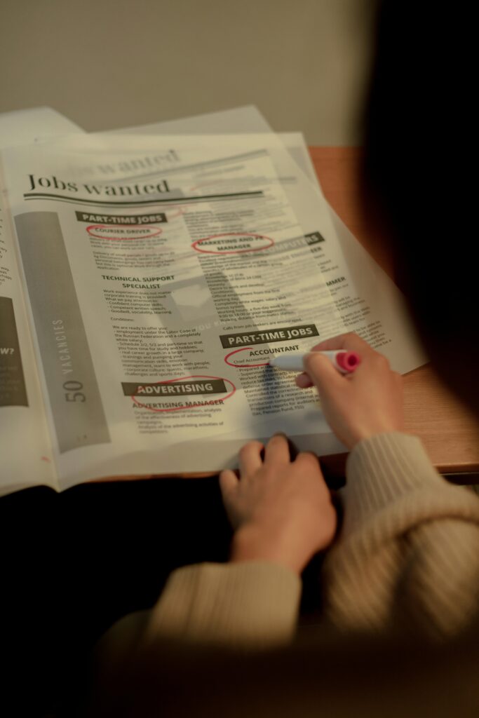 Close-up of a person marking job listings in a newspaper indoors.